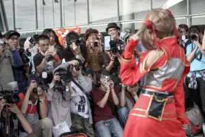 Crowd of enthusiastic photographers capturing photos of a cosplayer, showcasing the energy and excitement of a cosplay event. Photo by Tia Haygood.