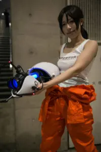 Portrait of a woman cosplaying with a Portal gun prop, showing creativity and attention to detail. Photo by Tia Haygood.