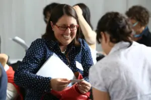 Joyful candid shot of a woman laughing and interacting with others, showcasing connection. Photo by Tia Haygood.