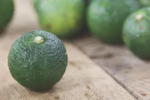 Close-up of fresh green yuzu fruit on a wooden surface, capturing the texture and natural appeal of this citrus.