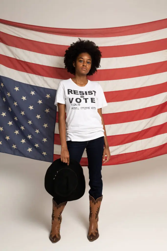 A portrait of a black woman wearing a shirt against racism, standing ahead of a country's flag - Tokyo Portrait Photographer