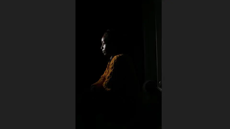 Headshot of a woman in an orange outfit inside a room with minimal light - Headshot photos, Charlotte portrait photographer