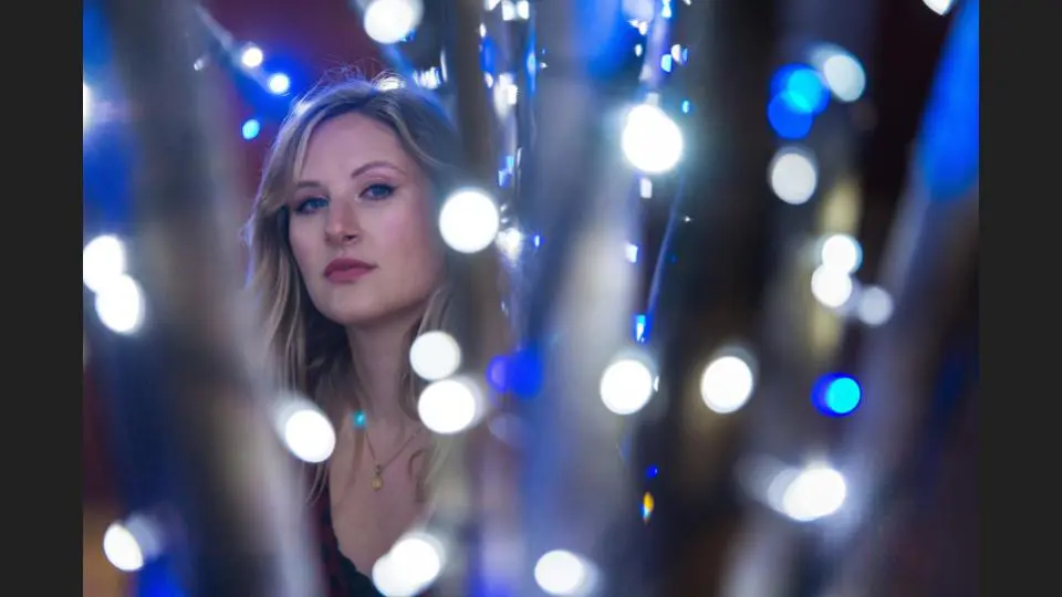 A focused portrait of a woman behind glowing string lights at an event - Tokyo Portrait Photographer, Photographer in Tokyo