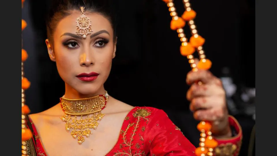 A bridal in a traditional red wedding outfit and jewelry staring at the mirror - family photography, lifestyle photography