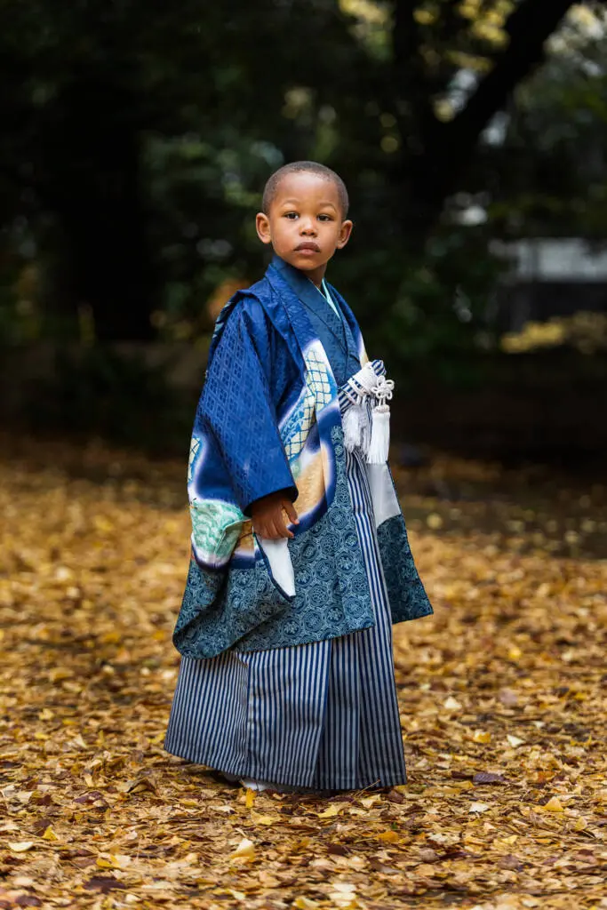 A young boy in a bautiful festive outfit standing in a garden with autumn leaves - family photography, Japan Photography