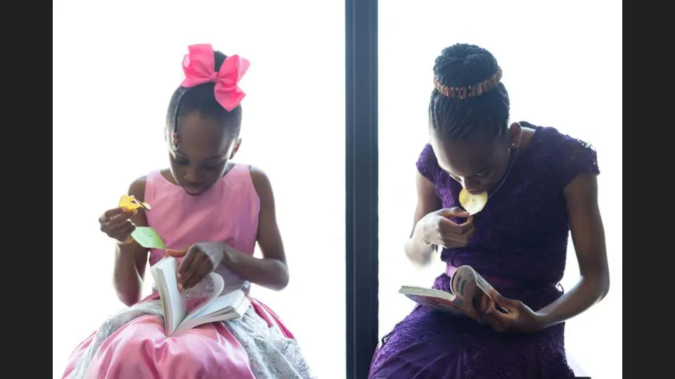 Two identical girls in unique purple and pink dresses looking in the notebooks - family photography, lifestyle photography