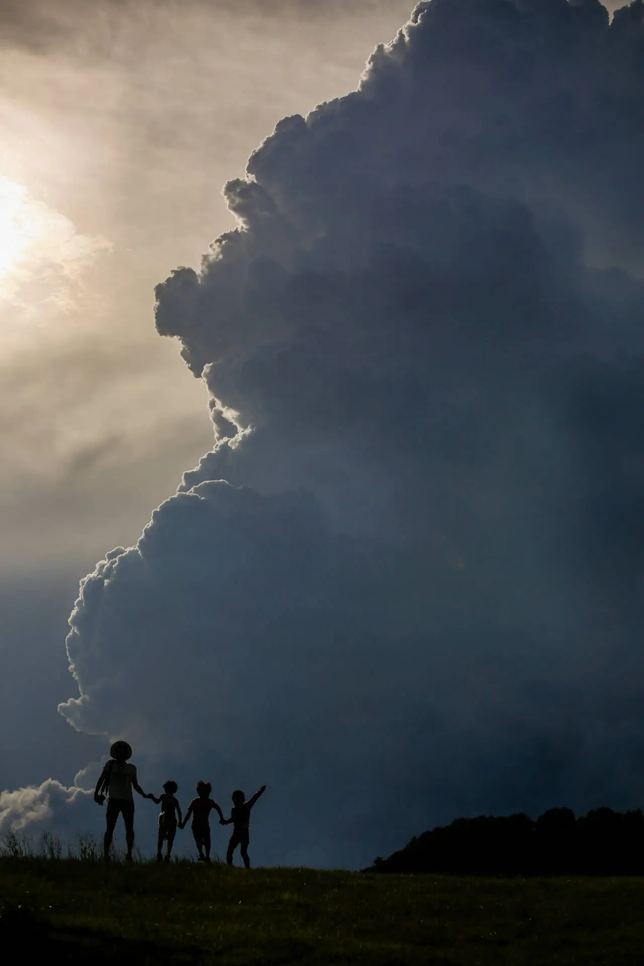 Far away shot of some kids playing around in a green hill area, a massive cloud stopping the sunlight - family photography, Tokyo Portrait Photographer, Photographer in Tokyo