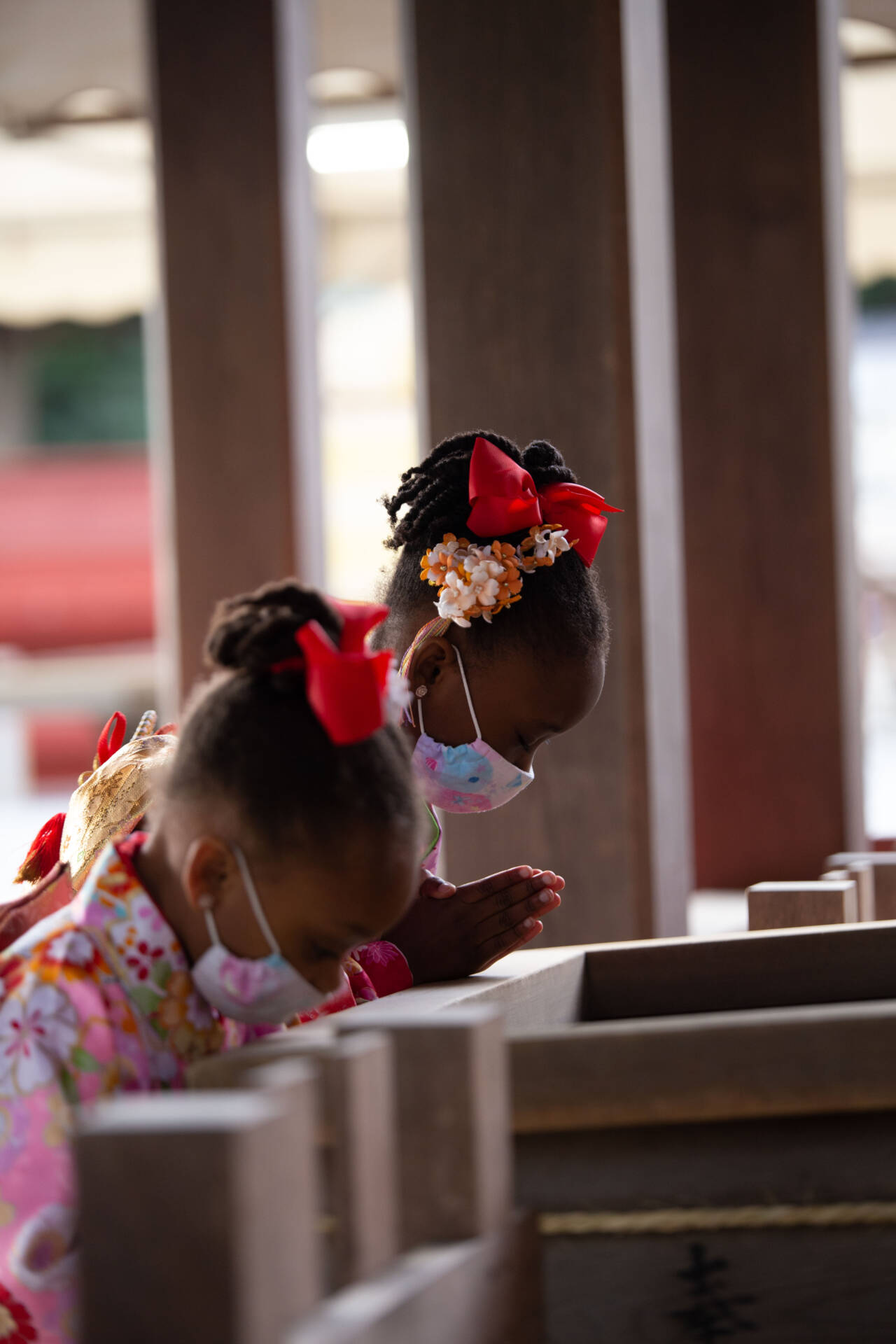 Masked girls praying at Japanese shrine.