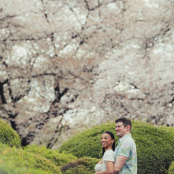A young couple in a green area posing in a backward hug with big smiles - Tokyo Portrait Photographer, Photographer in Tokyo