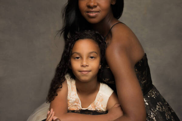 A black mother and a child posing for a picture in elegant gowns