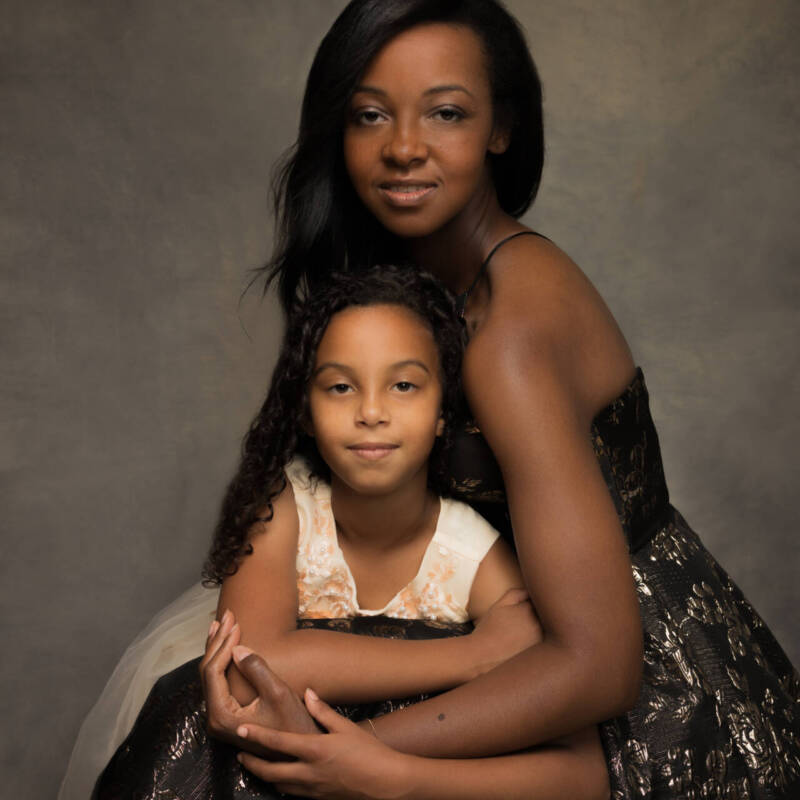 A black mother and a child posing for a picture in elegant gowns