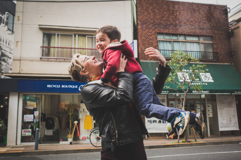 A happy father holding his happy son high in his hands on a street - family photography, lifestyle photography