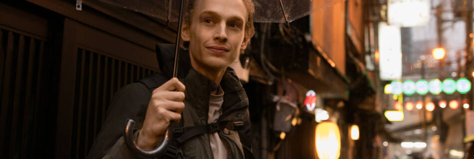 Young man with umbrella in Tokyo street, showcasing vibrant city life, Tokyo Portrait Photographer, Japan Photography