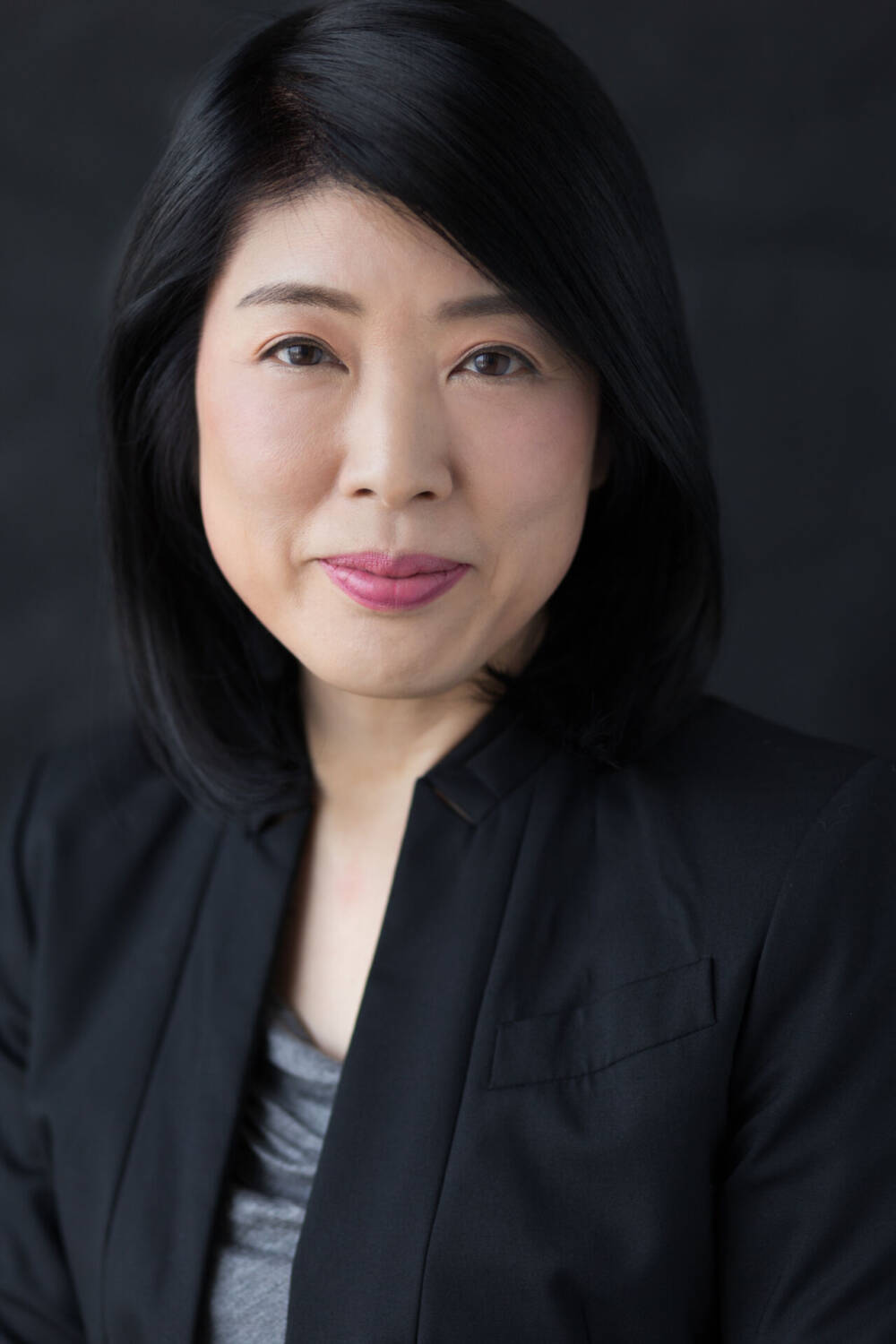 A close-up shot of a Japanese woman in black business formal attire, facing the camera - by Tokyo Portrait Photographer