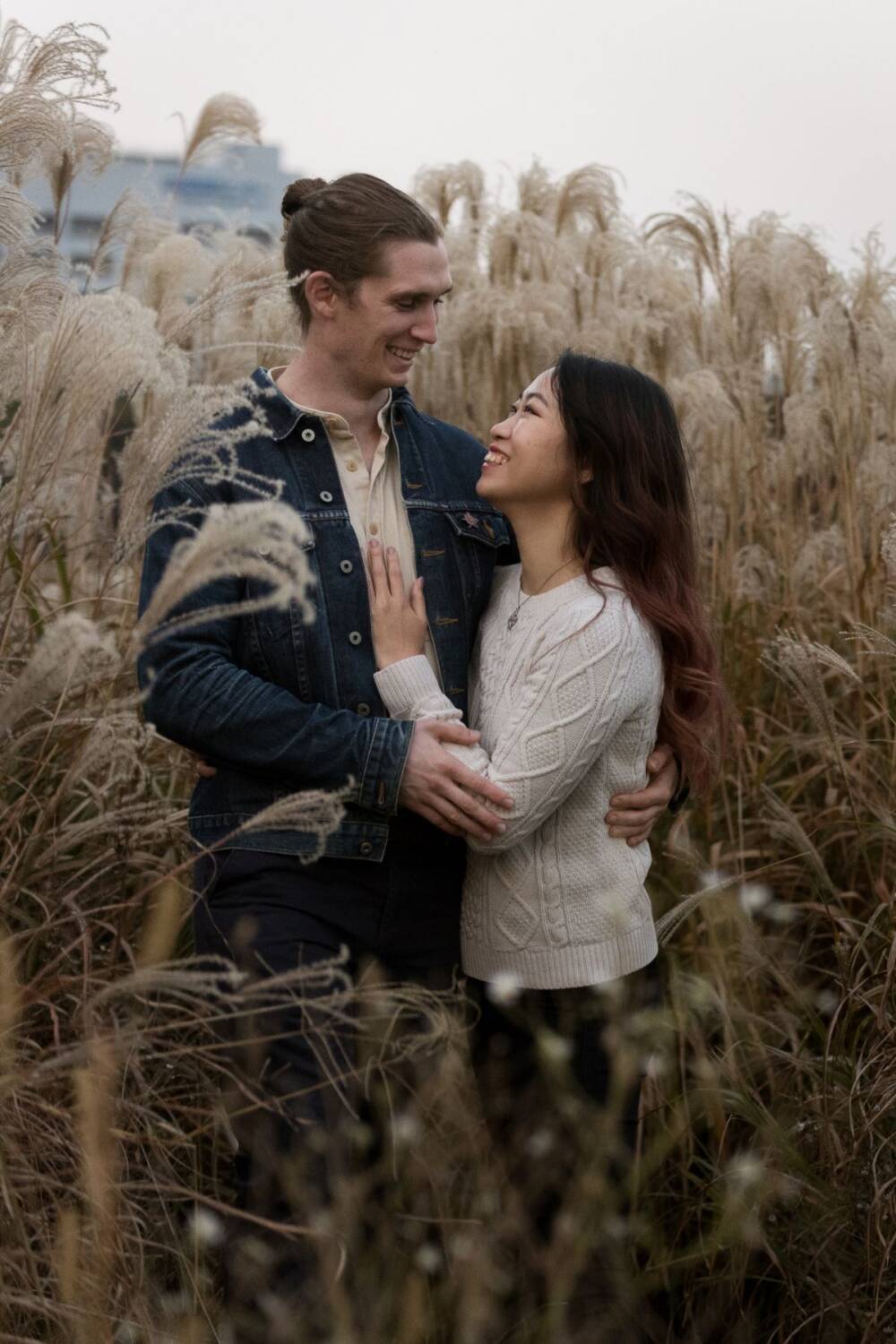 A young couple standing romantically within the meadow grass smiling - Tokyo Portrait Photographer, Photographer in Tokyo