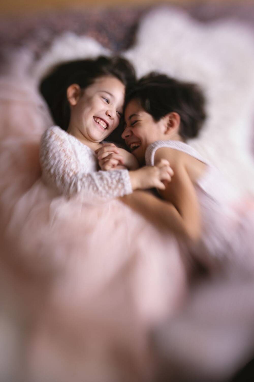 Fun-filled moment of two sisters playing with each, dreamy background, soft-focus - Children photography, TopTia