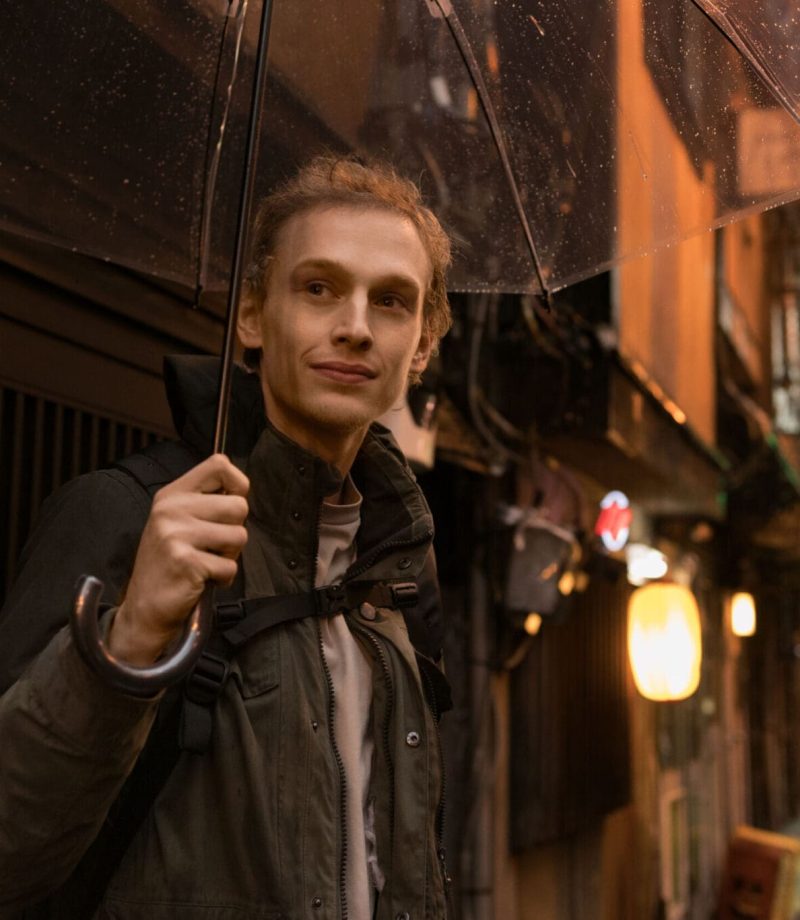 Young man with umbrella in Tokyo street, showcasing vibrant city life, Tokyo Portrait Photographer, Japan Photography