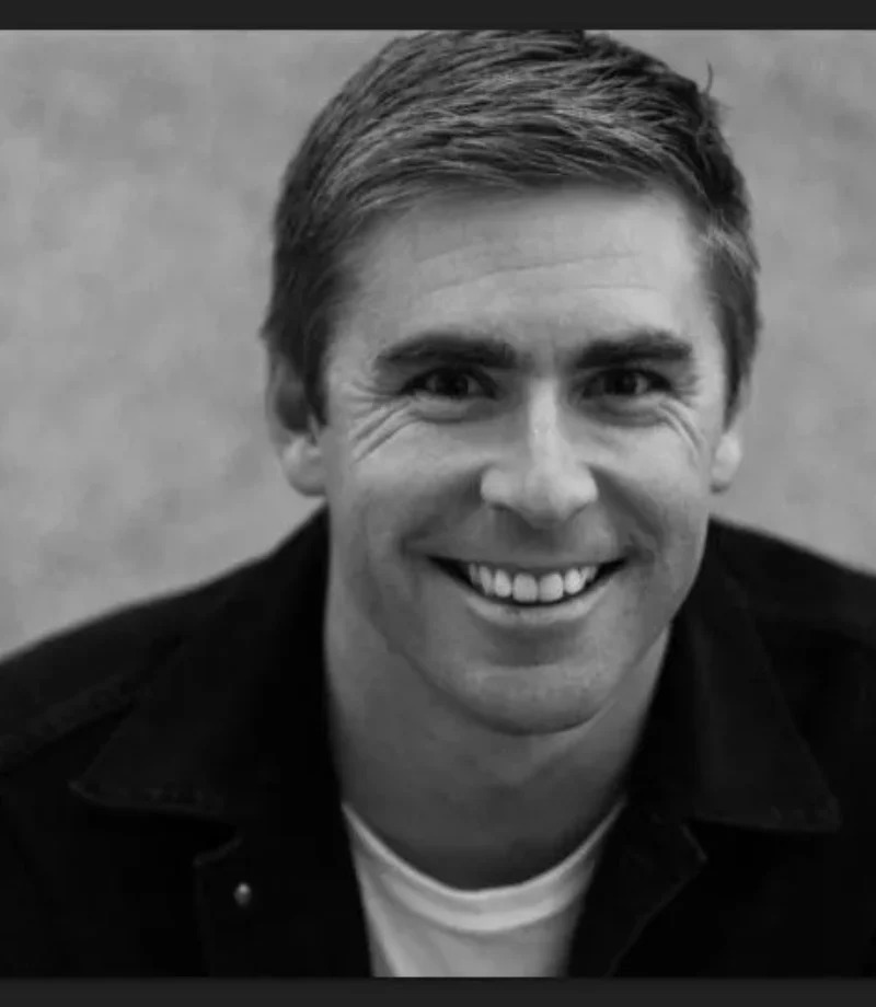 Black and white headshot of a young man in black coat smiling at the camera - Tokyo Portrait Photographer, Headshot photos